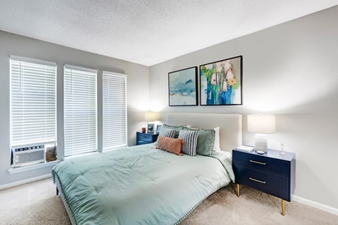 A bedroom with a bed, nightstand, and two wall lamps.