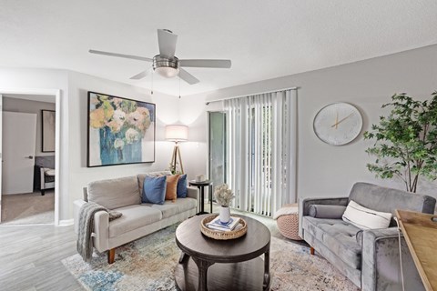 A living room with a grey couch, a coffee table, and a ceiling fan.