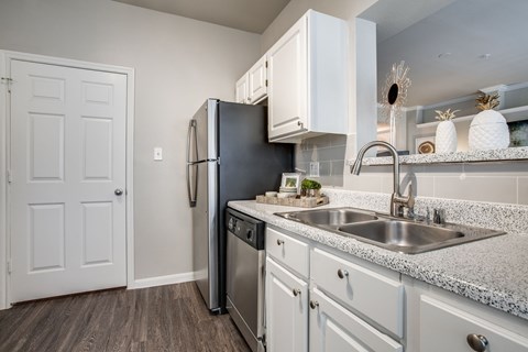 A kitchen with a black refrigerator and white cabinets.