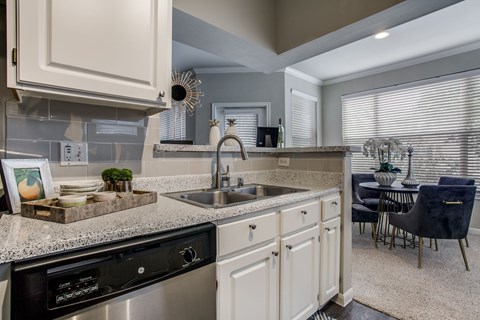 A kitchen with a black dishwasher and a sink with a faucet.