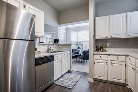 A kitchen with a stainless steel refrigerator and white cabinets.