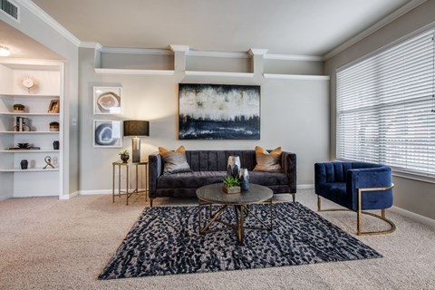 A living room with a grey couch, a blue chair, and a painting on the wall.