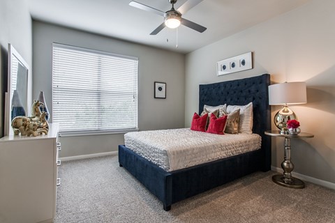 A bedroom with a bed, nightstand, and a ceiling fan.