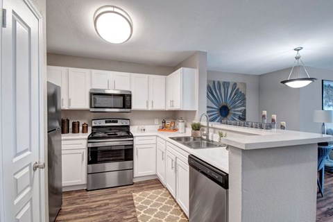 A modern kitchen with white cabinets and stainless steel appliances.