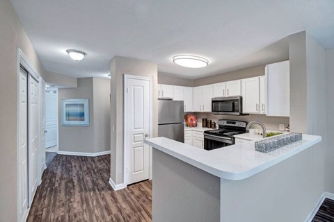 A kitchen with a white counter top and brown flooring.
