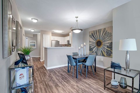 A modern living room with a dining area and a kitchen in the background.