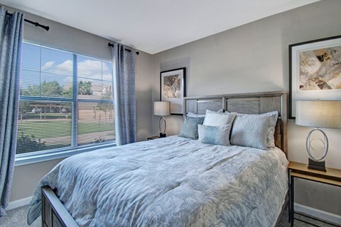 A bedroom with a large bed and a window with curtains.