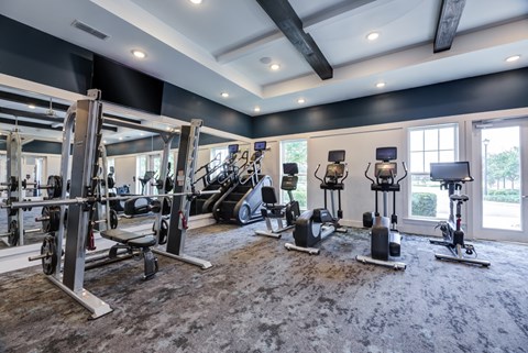 A spacious gym with a variety of equipment including treadmills, stationary bikes, and weight machines.