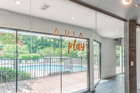 A glass door with a sign that says "ARLA Play" in front of a pool.