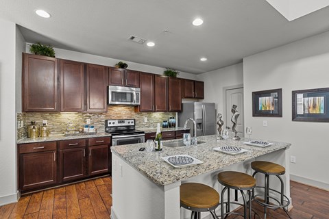 A kitchen with brown cabinets and a granite countertop.