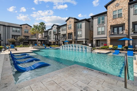 A swimming pool with a blue tiled edge and a fountain in the middle of it.