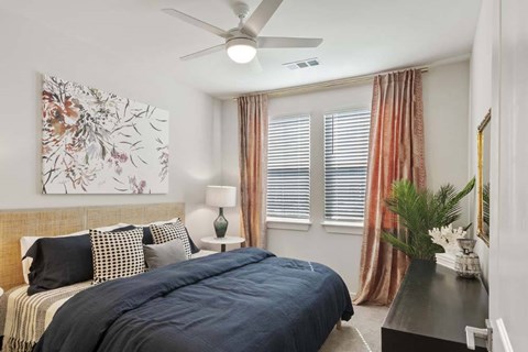 A bedroom with a large bed and a ceiling fan.