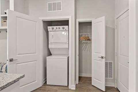 A white kitchen with a built in oven and a small closet.