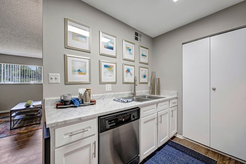 A kitchen with white cabinets and a marble countertop.