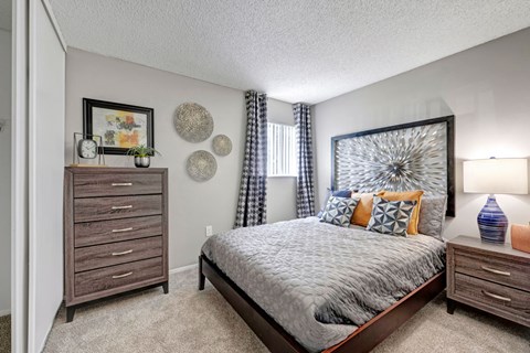A bedroom with a bed, nightstand, and a dresser.