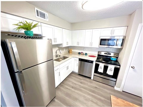 A kitchen with a stainless steel refrigerator and white cabinets.