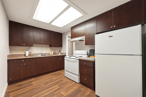 A kitchen with brown cabinets and a white fridge.