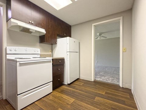 A kitchen with white appliances and wood floors.