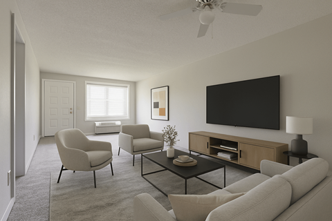 A living room with a grey sofa, two chairs, a coffee table, and a flat screen TV mounted on the wall.