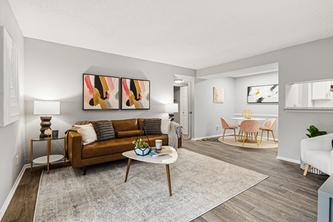 A living room with a brown couch, a coffee table, and a painting on the wall.