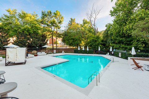 A swimming pool surrounded by trees and a white fence.