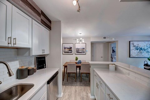 A kitchen with white cabinets and a wooden table.