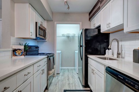 A kitchen with white cabinets and a black refrigerator.