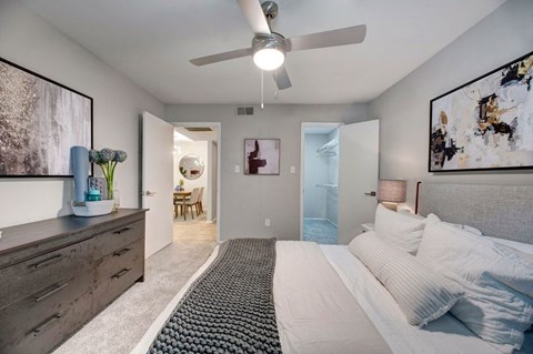A bedroom with a bed, dresser, and ceiling fan.