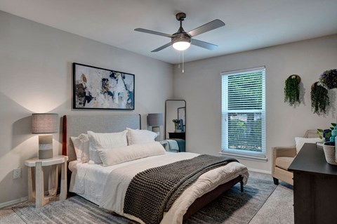 A bedroom with a large bed and a ceiling fan.