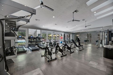 A gym with a variety of equipment including treadmills, stationary bikes, and weight machines.