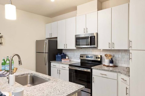 A kitchen with white cabinets and a black fridge.