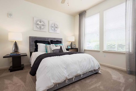 A bedroom with a large bed and two lamps.