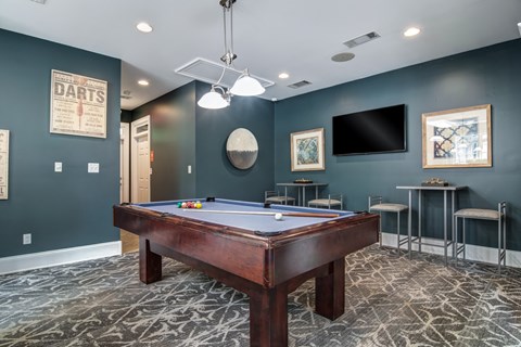 A pool table in a room with a TV and bar stools.
