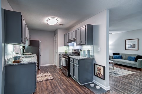 A kitchen with a refrigerator, oven, and sink.