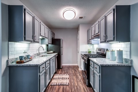 A kitchen with dark cabinets and a wooden floor.