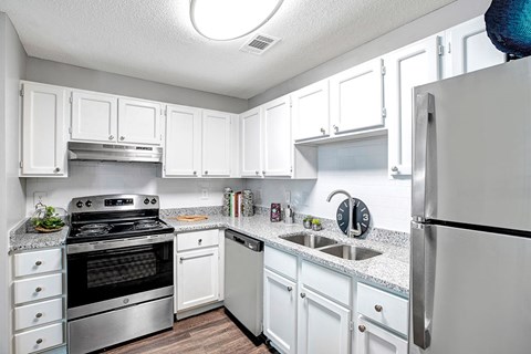 A kitchen with white cabinets and a stainless steel refrigerator.