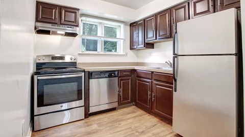 A kitchen with a white refrigerator, stainless steel oven and microwave, and wooden cabinets.