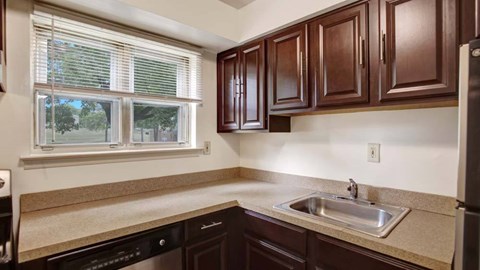 A kitchen with brown cabinets and a black dishwasher.