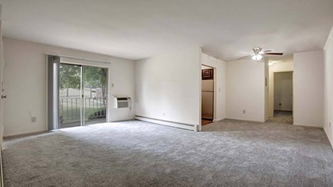 A spacious room with a carpeted floor and a ceiling fan.