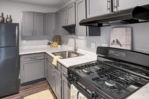 A kitchen with a black stove top oven and a black refrigerator.