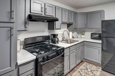 A kitchen with a black stove top oven and a black refrigerator.