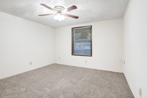 A room with a ceiling fan and a window with blinds.