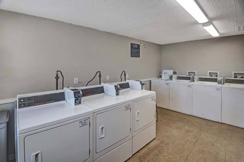 A laundromat with washers and dryers lined up.