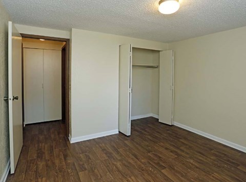 A room with wood flooring and two open doors.