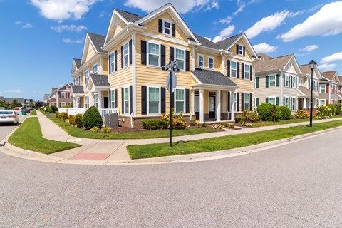A large, multi-story house with a red brick walkway in front.