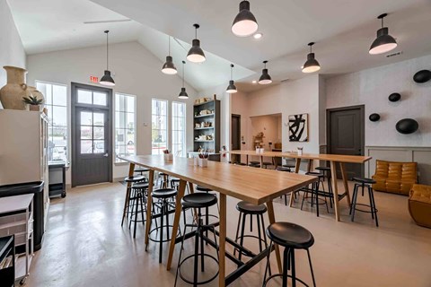 A modern dining area with a long table and bar stools.