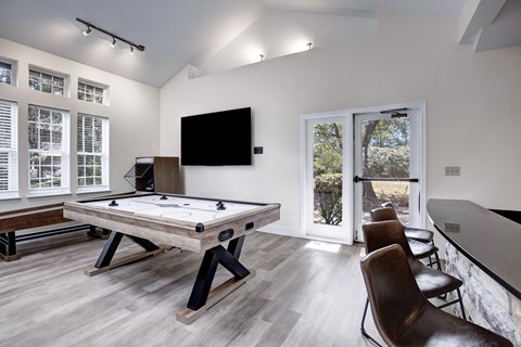A room with a pool table and a television.
