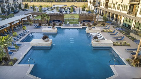 A large swimming pool surrounded by lounge chairs and palm trees.