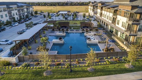 A large swimming pool surrounded by a wooden fence and a grassy area with trees.