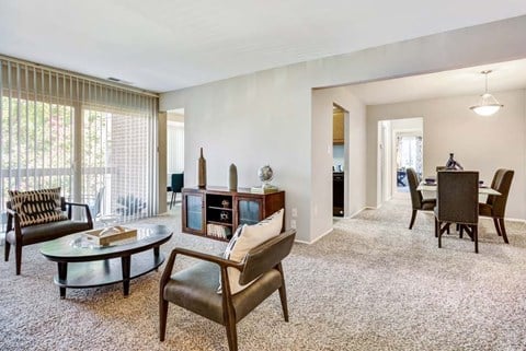 A living room with a glass table and leather chairs.